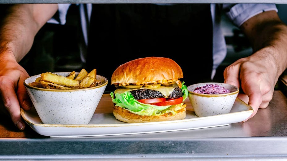Vegan burger and chips held by a chef at Twelve Eatery Bournemouth 